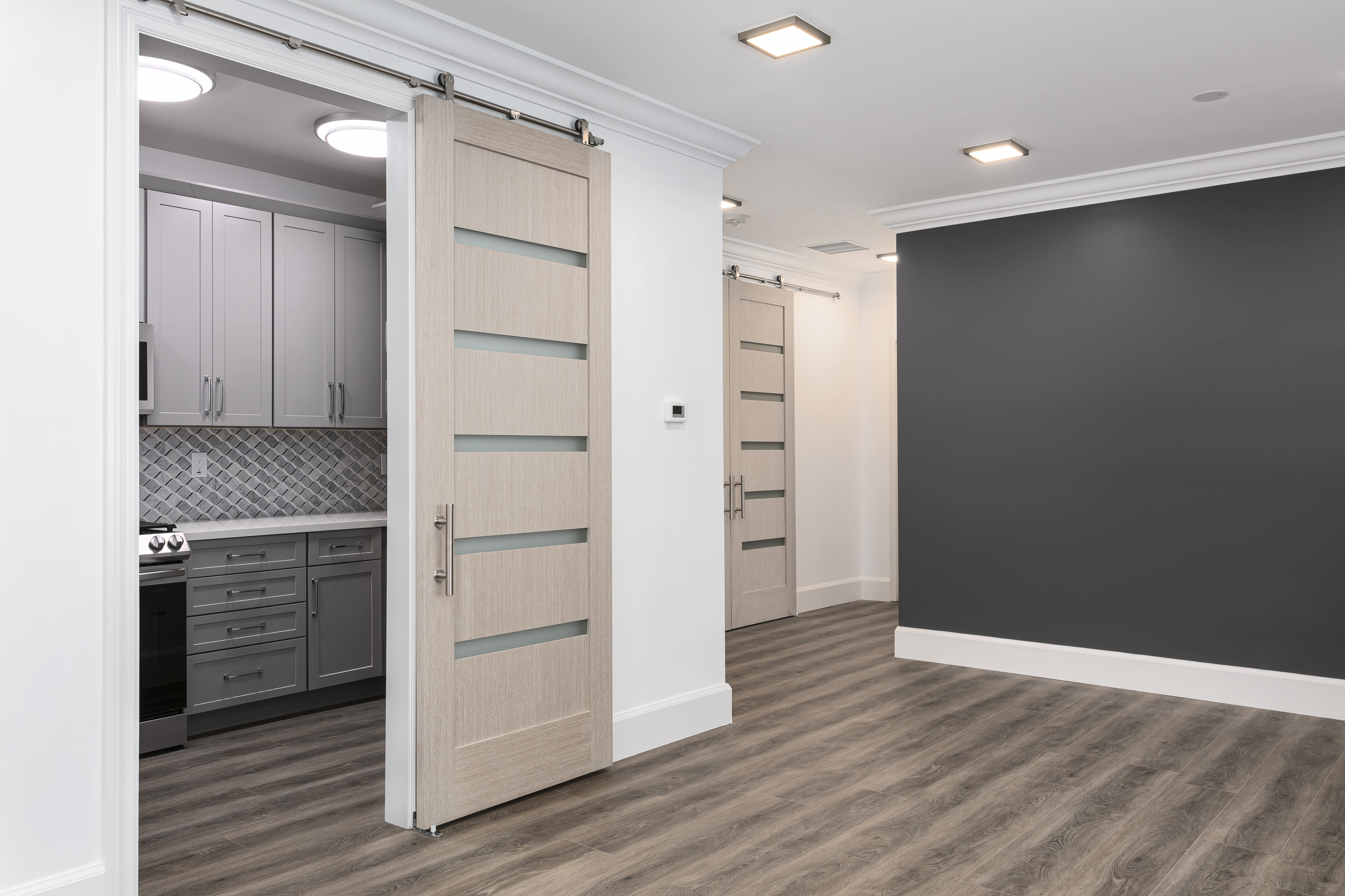 ADU open-plan kitchen and living area — sliding barn doors, grey cabinets