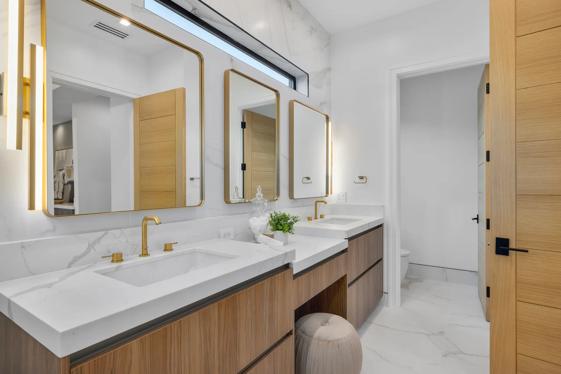 Primary bath with marble counters and brass fixtures — DWD Builders